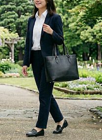 黒のトートバッグを持っているスーツ姿の女性の様子