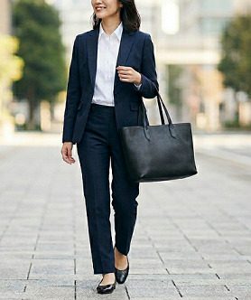 黒いトートバッグを持って、スーツで通勤する女性のイメージ