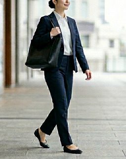 黒いトートバッグを持って通勤するスーツ姿の女性のイメージ
