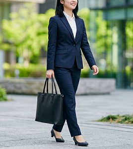 オフィス街を歩く、黒いトートバッグを持ったスーツ姿の女性