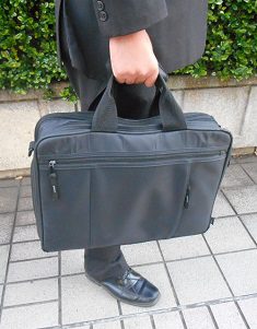 ファスナー付きビジネスバッグを持つ通勤シーン