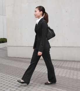 黒のリクルートスーツにトートバッグを合わせた女性の歩行シーン