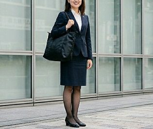 黒の軽量トートバッグを肩にかけた紺色スーツの就活女性
