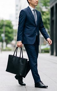 スーツ姿で通勤バッグを持って歩く男性