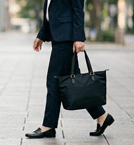 街中を、黒いトートバッグを持って、通勤している女性のイメージ
