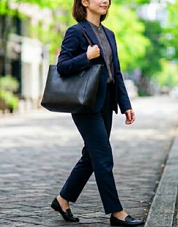 街を歩く、黒のトートバッグを持ったスーツ姿の女性
